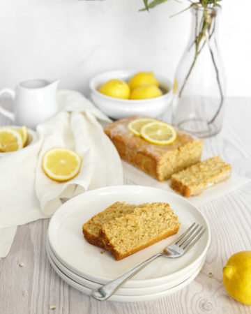 A sliced, Low FODMAP Lemon Loaf with Collagen and a lemon glaze, garnished with lemon.