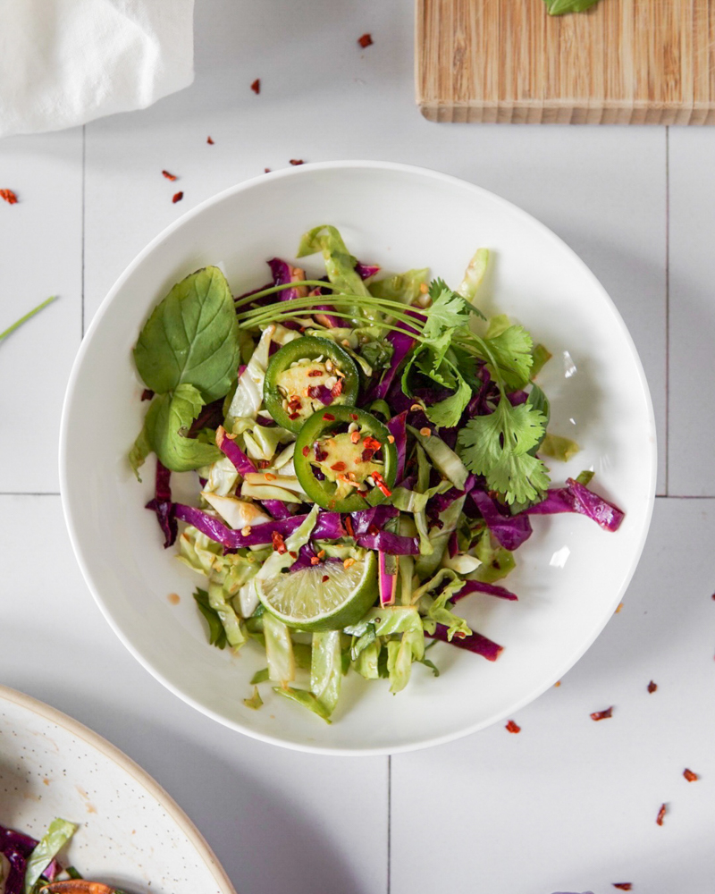 A bowl of simple, light and refreshing Asian-Style Coleslaw topped with jalapenos, mint and lime.