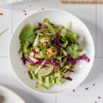 A bowl of simple, light and refreshing Asian-Style Coleslaw topped with jalapenos, mint and lime.