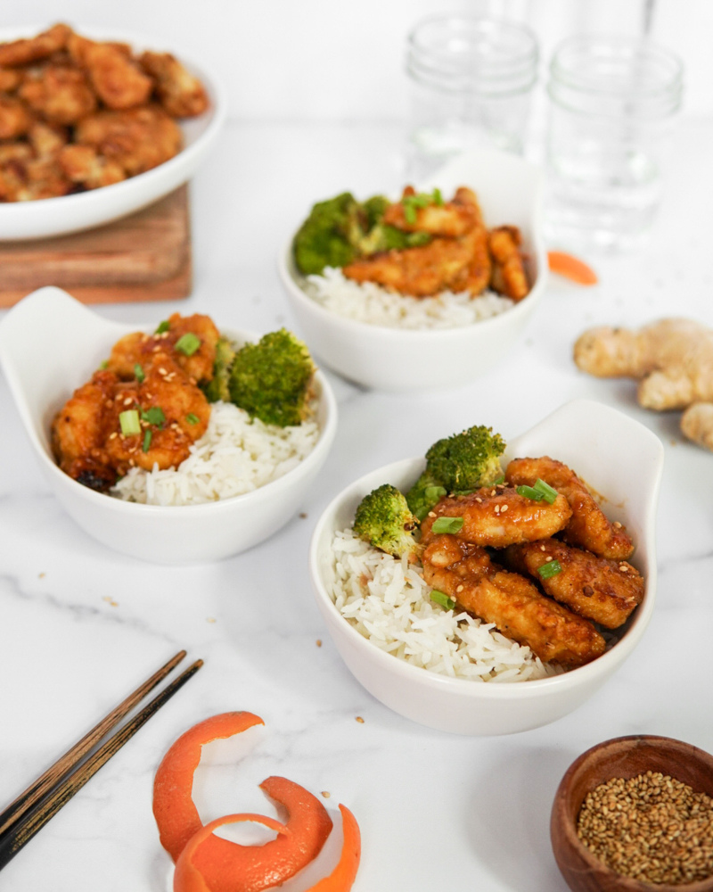 Bowls of rice topped with Low FODMAP & Paleo Orange Chicken.