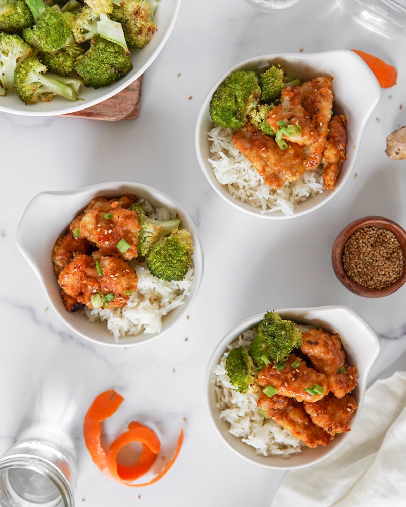 Bowls of rice topped with Low FODMAP & Paleo Orange Chicken.