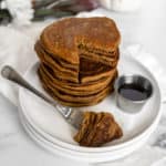 A stack of Low FODMAP & Paleo Pumpkin Pancakes with a slice ready to be eaten.