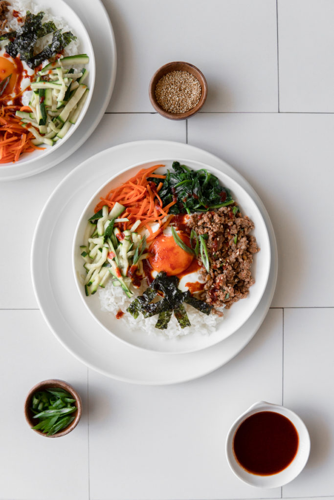 Easy Low FODMAP Bibimbap with Ground Beef and sauteed zucchini, carrot & spinach, topped with a fried egg, and a Low FODMAP sauce, served over rice.