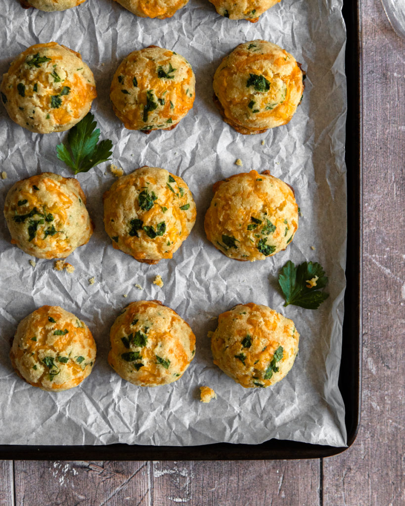 A baking tray of Low FODMAP cheddar buns, topped with parsley.