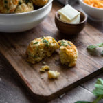 A tray of Low FODMAP cheddar buns, topped with parsley, with a side of butter.