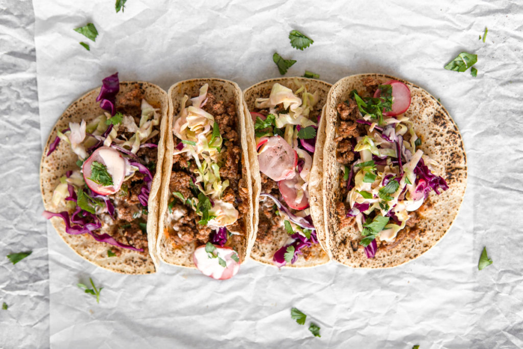A row of Low FODMAP ground beef bugolgi tacos, topped with quick pickled cabbage and sriracha mayo.