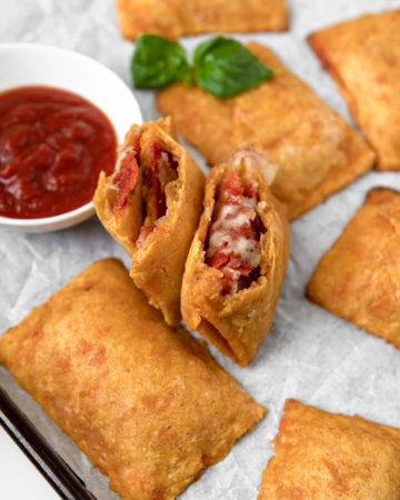 A Low FODMAP & Grain Free homemade pizza roll filled with passata, pepperoni and mozzarella, ripped open to show the hot and saucy insides.